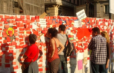 스페인의 시위참가자들이 담벼락에 붙은 글들을 유심히 보고 있다