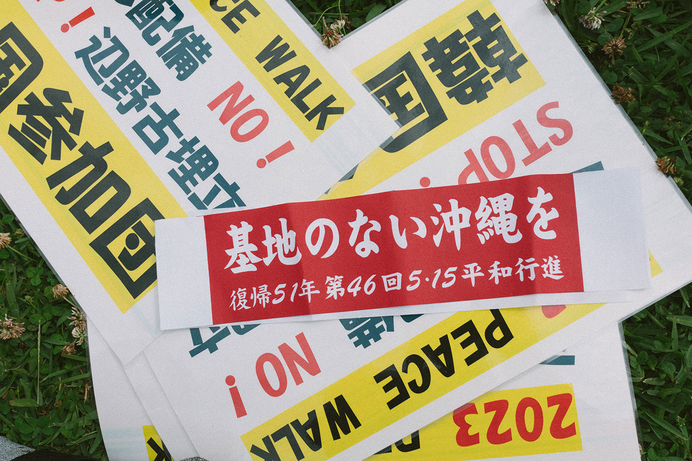 바닥에 일본어로 적힌 여러 피켓이 놓여있다. 뒤쪽에 있는 피켓에는 '2023 peace walk, 한국참가단'이라고 적혀있고, 앞쪽에 있는 피켓에는 '기지가 없는 오키나와를, 복귀 51년 제46회 5.15 평화행진'이라고 적혀있다.