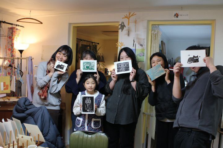 6명의 사람들이 실내에서 판화를 들고 있는 모습을 촬영한 사진이다. 